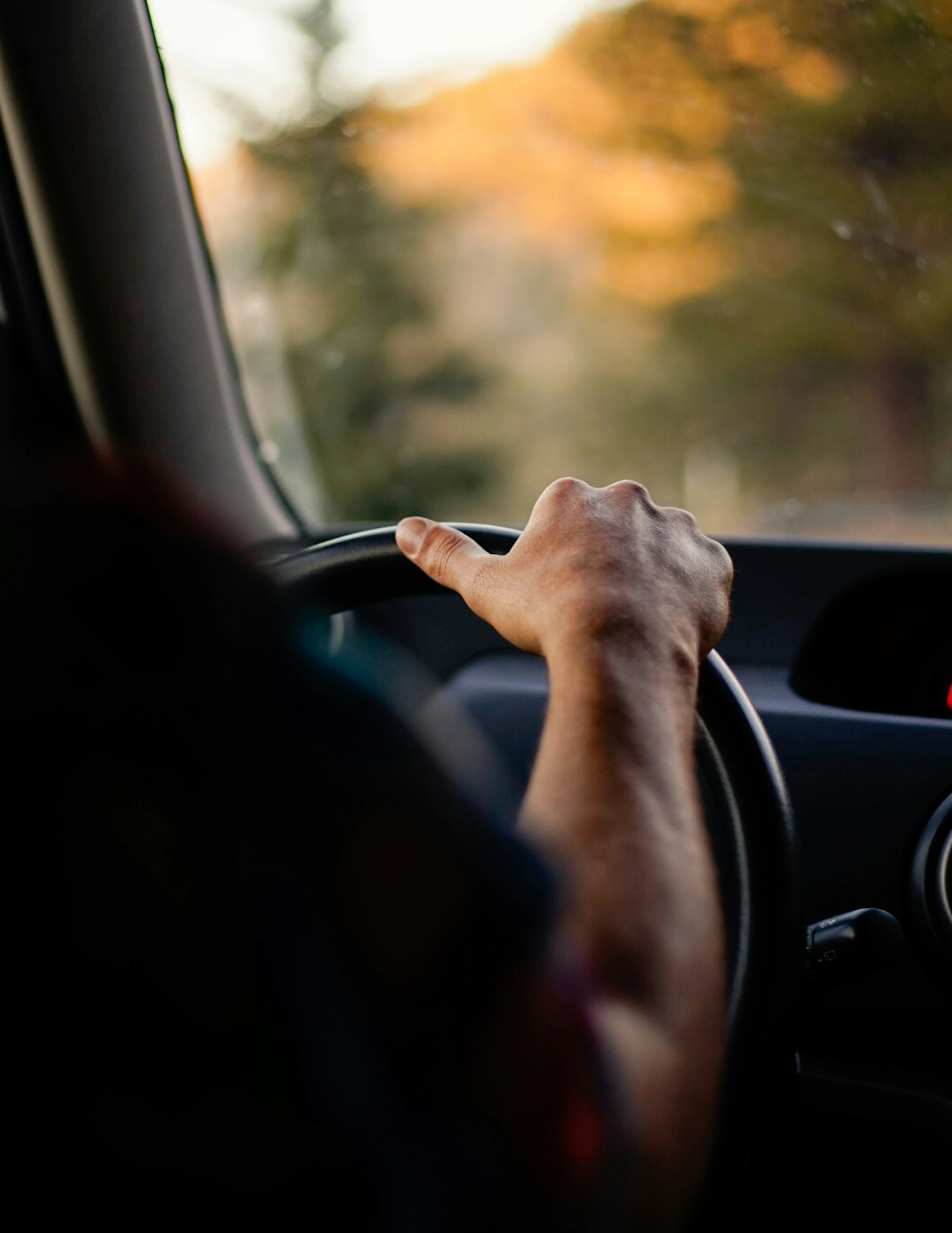 Chauffeur service KL & Selangor. Driver hand on the steering wheel at golden hour.