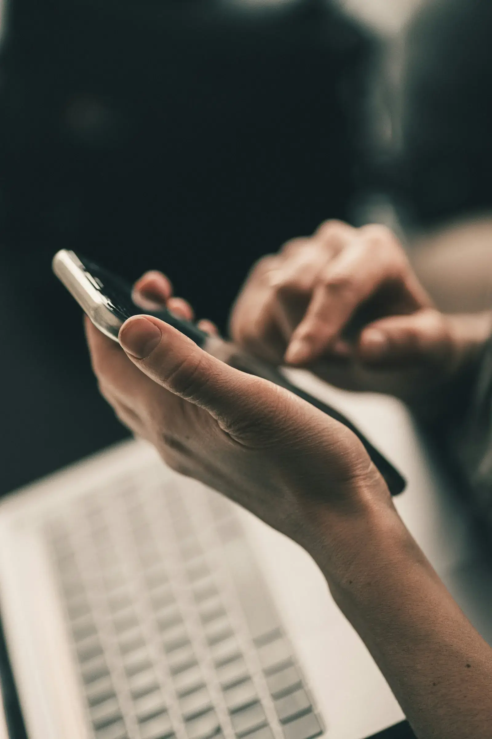 Hands using a smartphone beside a laptop to contact Maha Empire Car Rental
